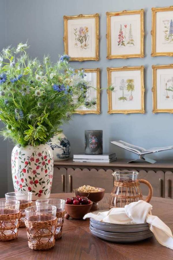 Dining table with wildflowers, rattan glassware, and botanical prints