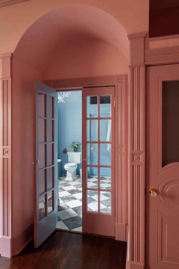 Pink arched hallway opening to the blue bath
