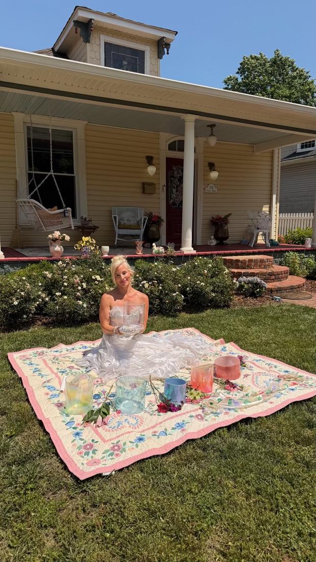 Claire seated on a quilt in the garden with crystal singing bowls
